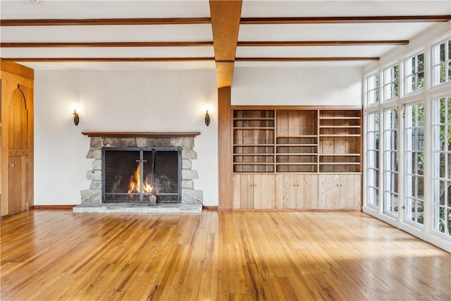 unfurnished living room featuring beam ceiling, baseboards, a fireplace, and hardwood / wood-style floors