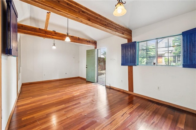 spare room featuring beamed ceiling, wood-type flooring, and baseboards