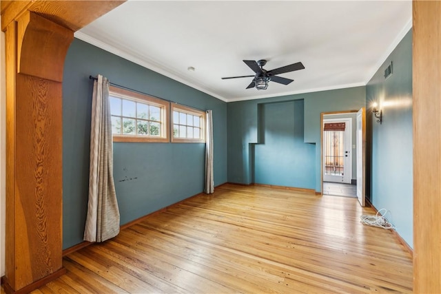 spare room with ceiling fan, light wood-type flooring, visible vents, and crown molding