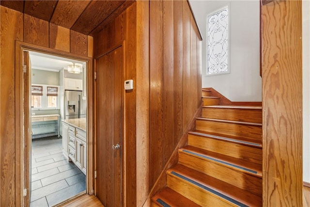 stairs featuring wood walls and wood finished floors