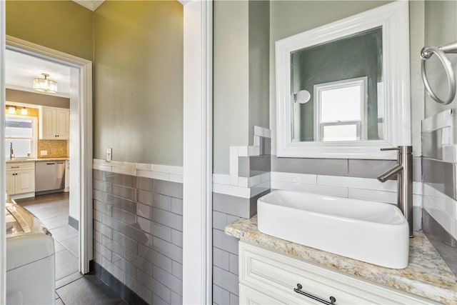 full bathroom with wainscoting, washer / dryer, tile walls, and vanity