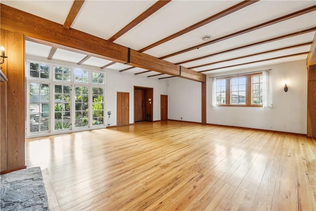 unfurnished living room with beamed ceiling, light wood-type flooring, and baseboards