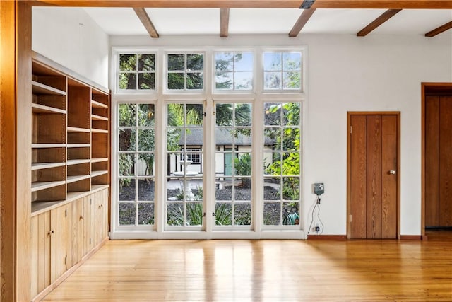 doorway with beamed ceiling, wood finished floors, and baseboards