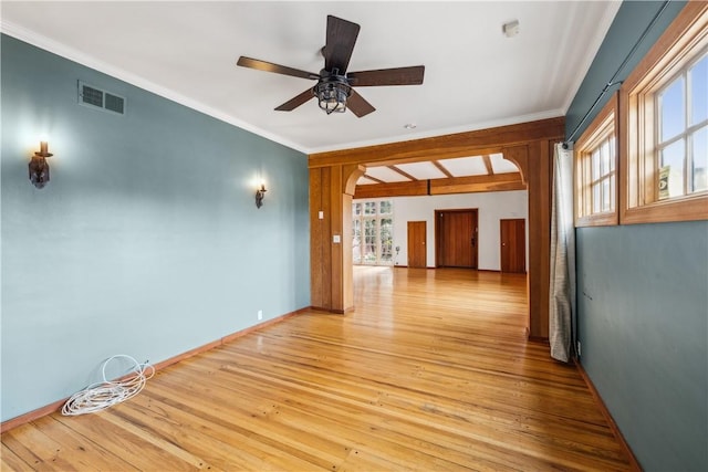 spare room featuring ceiling fan, wood finished floors, visible vents, baseboards, and crown molding