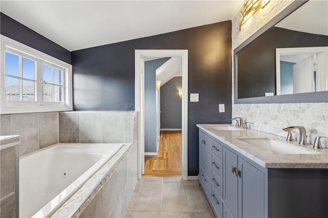 full bath with double vanity, a jetted tub, tile patterned flooring, and a sink