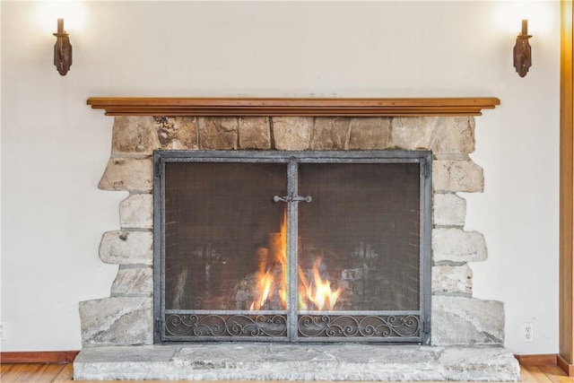 details with a lit fireplace, baseboards, and wood finished floors