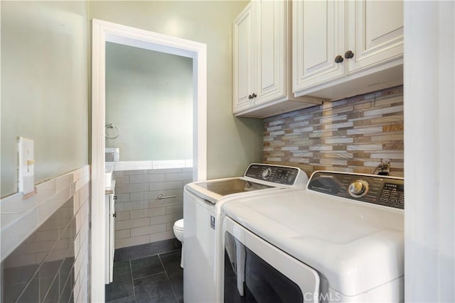 2749 E 17th St, Oakland, CA 94601 - laundry room featuring separate washer and dryer, tile walls, dark tile patterned flooring, and a wainscoted wall