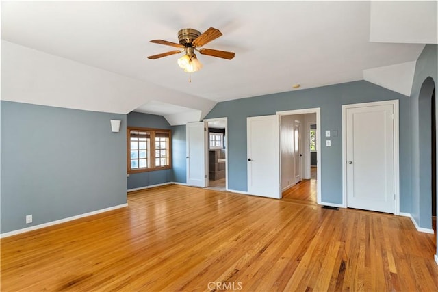 2749 E 17th St, Oakland, CA 94601 - unfurnished bedroom with light wood-style flooring, vaulted ceiling, arched walkways, ceiling fan, and two closets