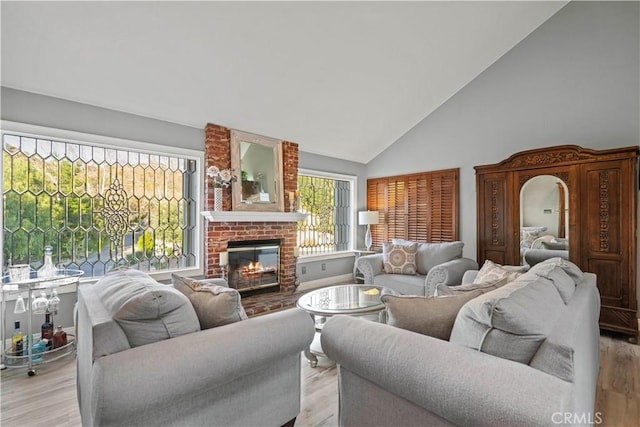 living area featuring light wood-style floors, a brick fireplace, and high vaulted ceiling