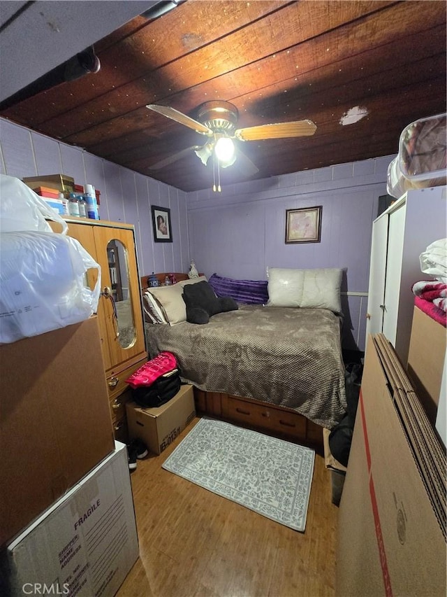 bedroom featuring a ceiling fan, a decorative wall, and wood finished floors