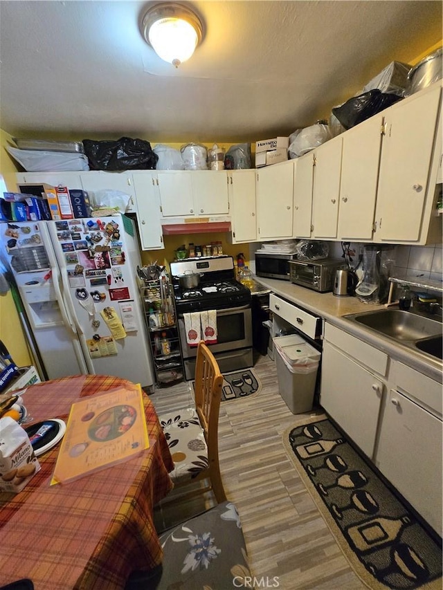 kitchen featuring white cabinets, stainless steel appliances, a sink, and light countertops