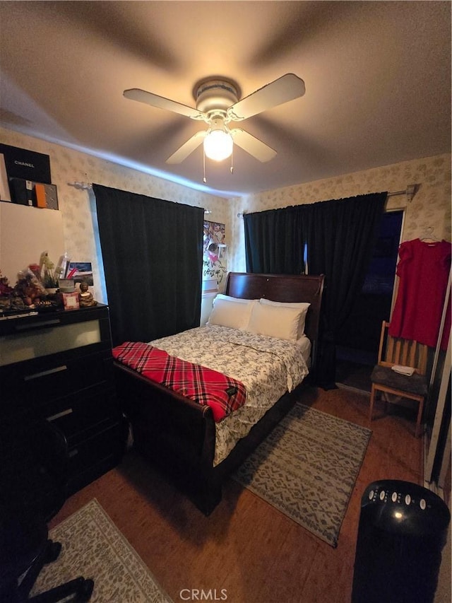 bedroom with wallpapered walls, ceiling fan, and wood finished floors