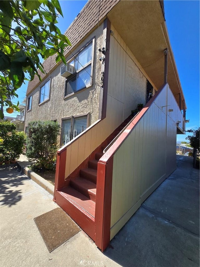 view of side of home with stairs and stucco siding