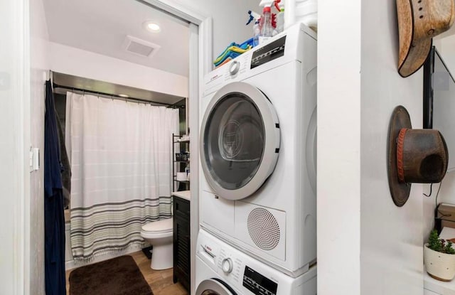 clothes washing area featuring light wood finished floors, laundry area, visible vents, stacked washer and clothes dryer, and recessed lighting