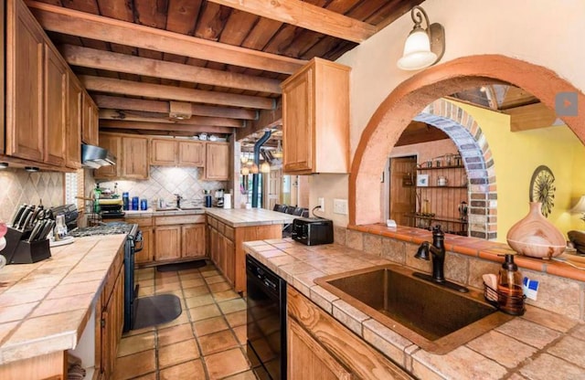 kitchen featuring tile counters, a sink, under cabinet range hood, and black appliances