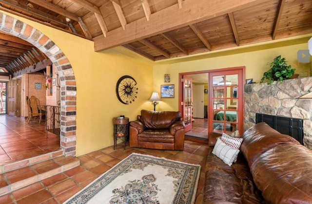 tiled living area featuring arched walkways, wooden ceiling, a fireplace, and beam ceiling