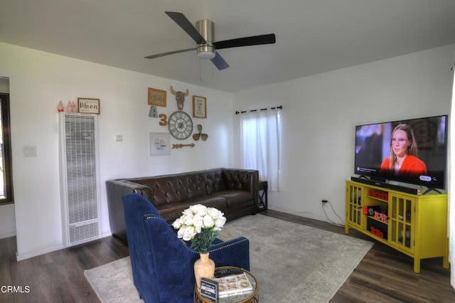 living area with ceiling fan, a heating unit, wood finished floors, and baseboards