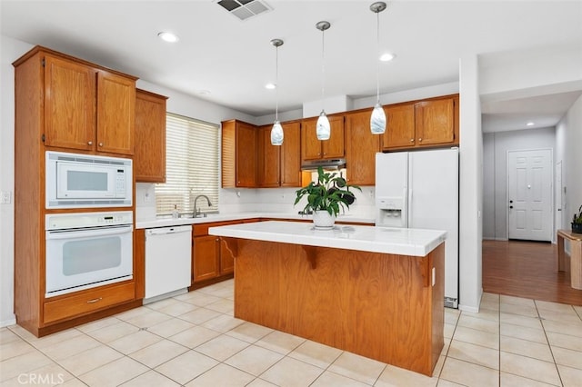 kitchen featuring white appliances, visible vents, a kitchen island, brown cabinets, and light countertops