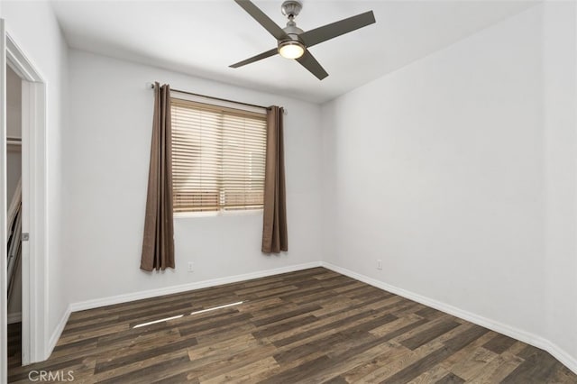 empty room featuring dark wood finished floors, a ceiling fan, and baseboards