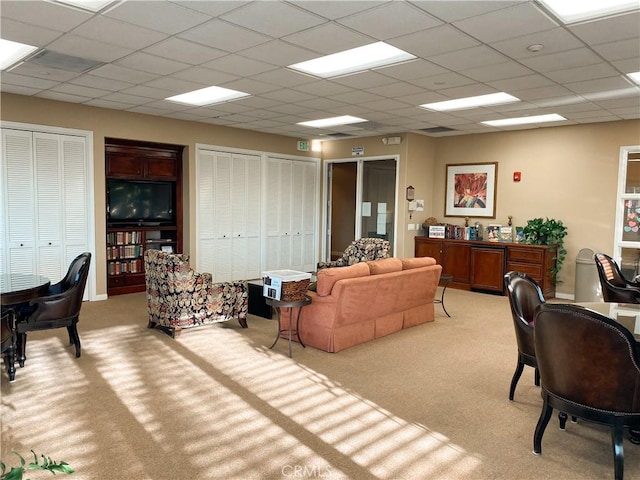 living room featuring light colored carpet and a drop ceiling