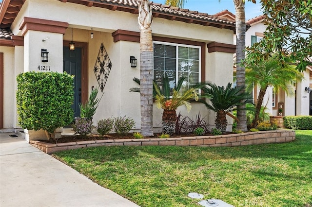 view of front of home featuring a tiled roof, a front lawn, and stucco siding