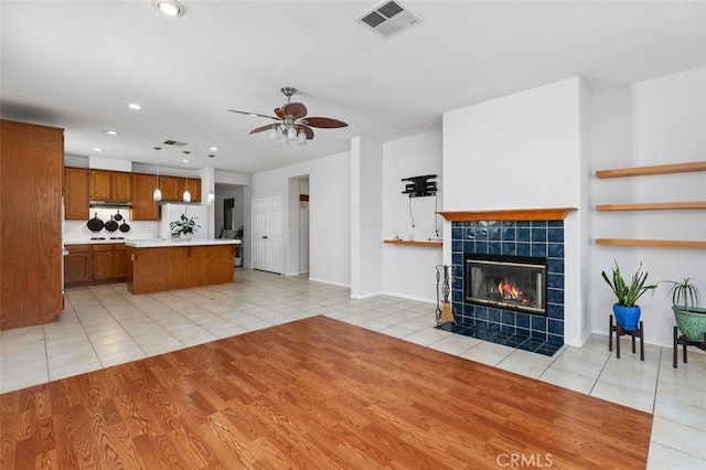 unfurnished living room with ceiling fan, light tile patterned flooring, recessed lighting, visible vents, and a tiled fireplace