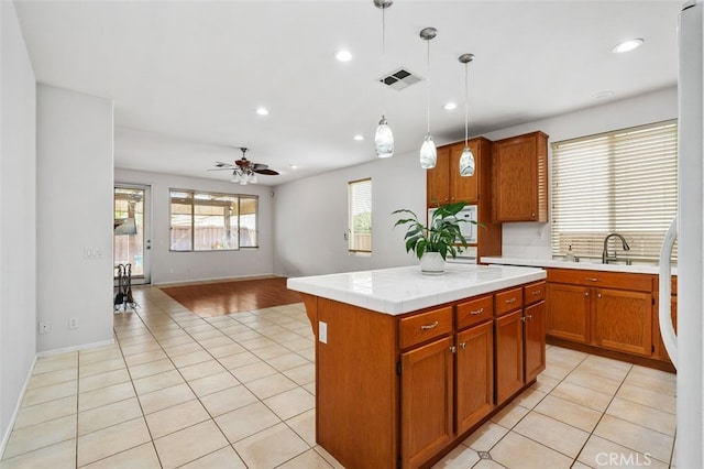 kitchen with brown cabinetry, visible vents, hanging light fixtures, and light tile patterned floors