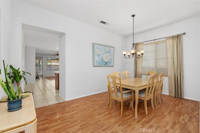 dining area featuring light wood-type flooring, baseboards, visible vents, and ceiling fan with notable chandelier