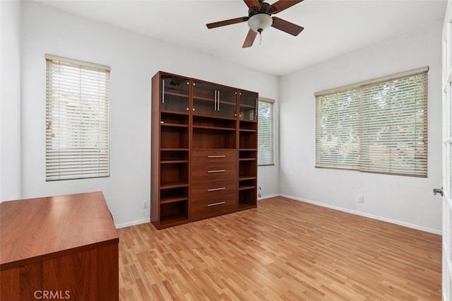 unfurnished bedroom with multiple windows, light wood-type flooring, and baseboards