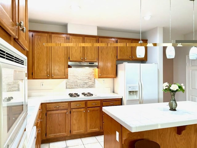 41211 Crooked Stick Dr, Temecula, CA 92591 - kitchen featuring white appliances, brown cabinets, under cabinet range hood, and recessed lighting