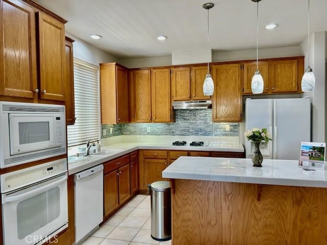 41211 Crooked Stick Dr, Temecula, CA 92591 - kitchen with white appliances, under cabinet range hood, brown cabinets, tile counters, and pendant lighting