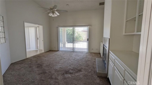 interior space featuring carpet, a high ceiling, visible vents, and ceiling fan