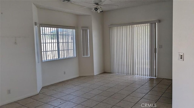 unfurnished room featuring ceiling fan, baseboards, a textured ceiling, and light tile patterned flooring