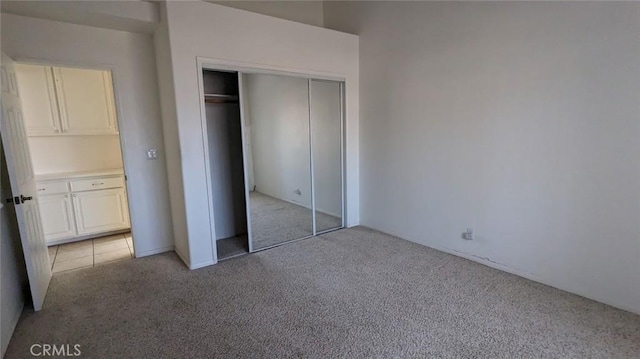 unfurnished bedroom with a closet and light carpet