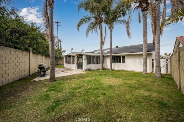 back of property with a lawn, a sunroom, a fenced backyard, a patio area, and stucco siding