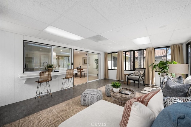 living area featuring a wealth of natural light and a drop ceiling
