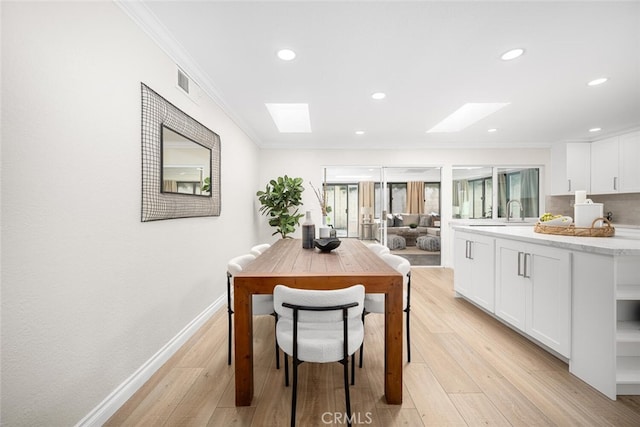 dining area with crown molding, recessed lighting, a skylight, and baseboards