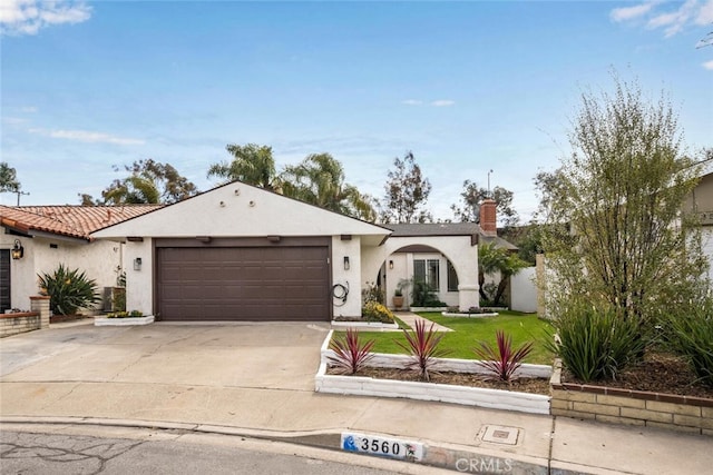 view of front of house with a front lawn, driveway, an attached garage, and stucco siding