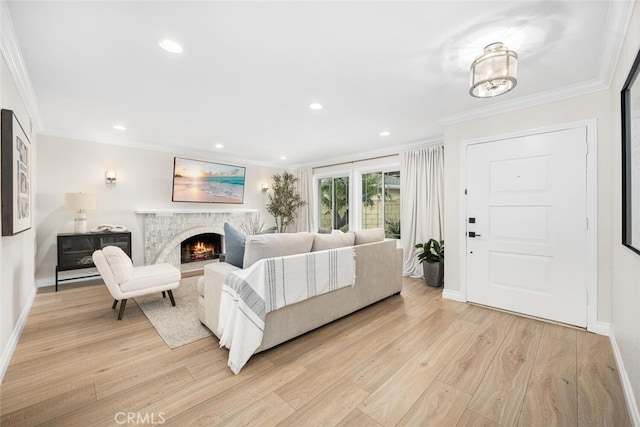 living room with a lit fireplace, light wood finished floors, and crown molding