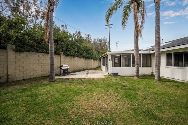 view of yard featuring a sunroom, a fenced backyard, and a patio