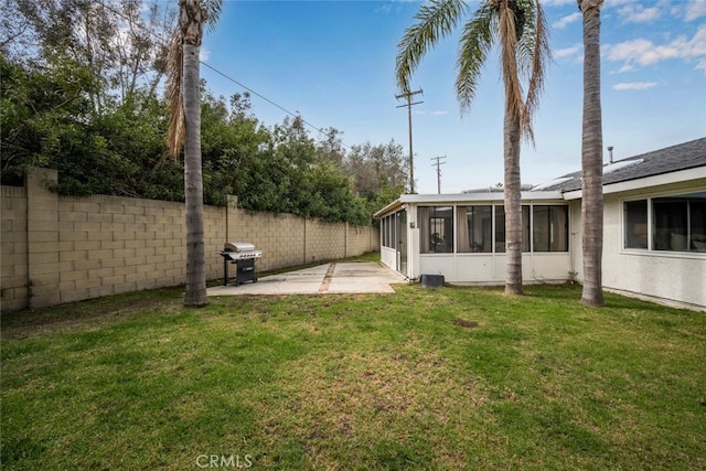 view of yard featuring fence, a sunroom, and a patio area