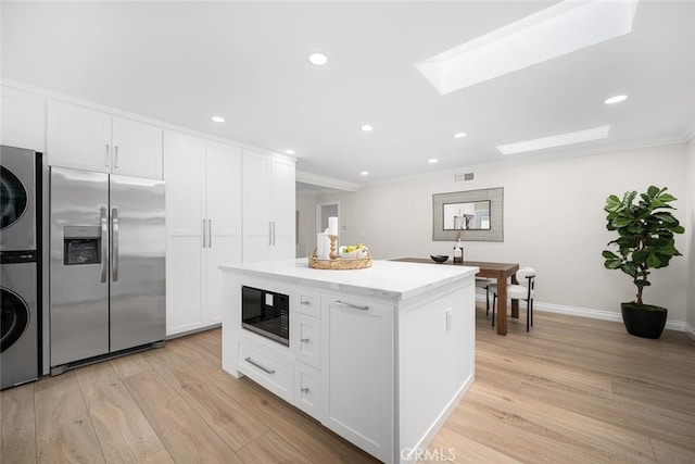 kitchen featuring stacked washer and clothes dryer, stainless steel fridge, black microwave, and white cabinets