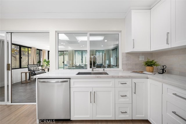kitchen featuring stainless steel dishwasher, light stone countertops, a sink, and white cabinetry
