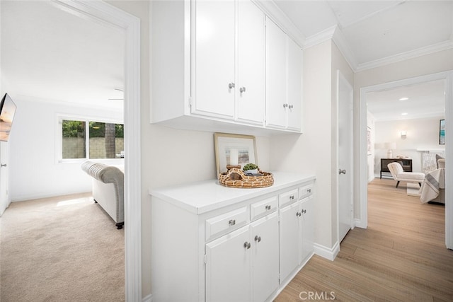 hallway featuring light wood-style floors, baseboards, and crown molding