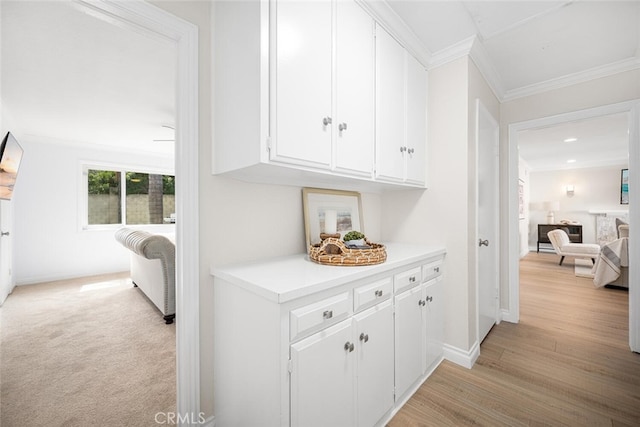 hallway with crown molding, light wood finished floors, and baseboards