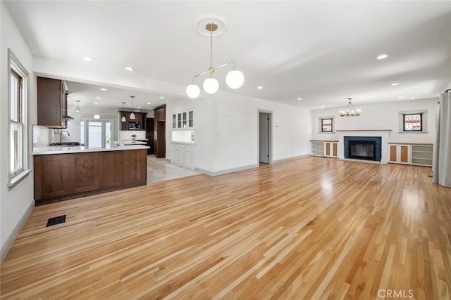 unfurnished living room with visible vents, recessed lighting, light wood-style floors, and a sink