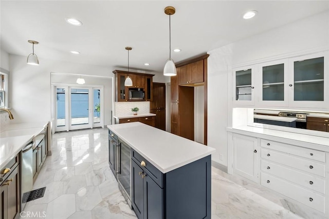 kitchen with glass insert cabinets, marble finish floor, stainless steel appliances, and light countertops