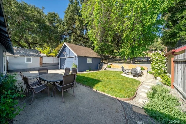 view of yard with a patio, an outdoor structure, outdoor dining space, and fence