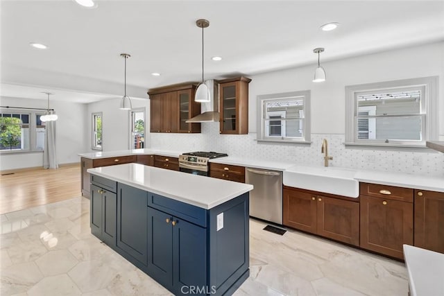 kitchen with glass insert cabinets, stainless steel appliances, light countertops, and a sink