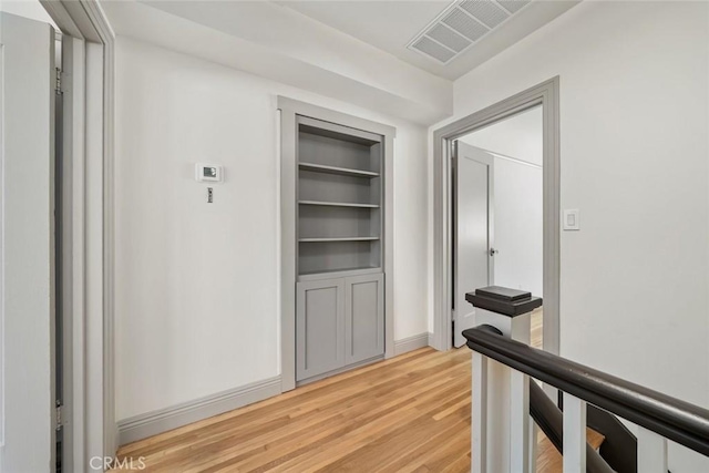 hallway featuring an upstairs landing, visible vents, light wood-style flooring, and baseboards